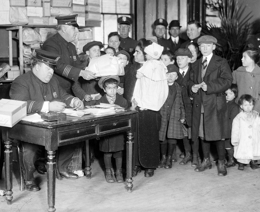 Policías distribuyendo regalos a familias, con pocos recursos, del distrito. 1915. Biblioteca del Congreso